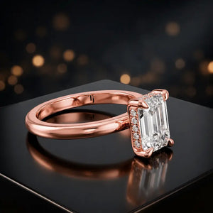 Angled view of 4-claw emerald cut engagement ring with hidden halo in 18kt rose gold