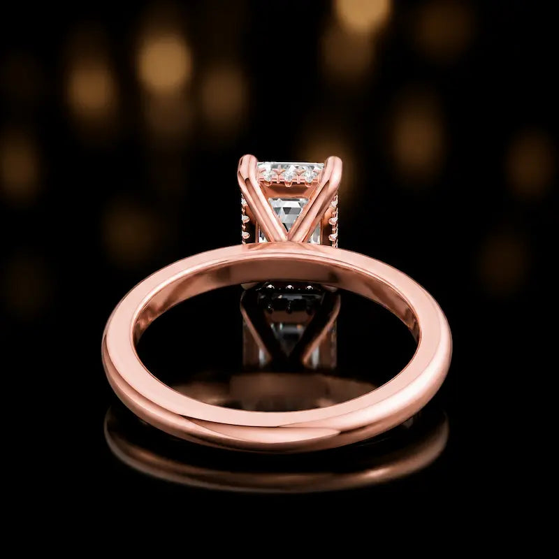 Back view of 4-claw emerald cut engagement ring with hidden halo in 18kt rose gold