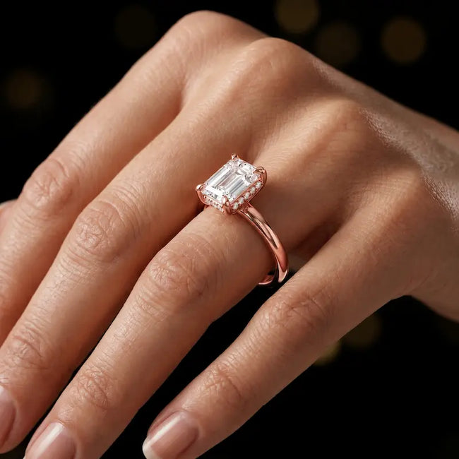 4-claw emerald cut engagement ring with hidden halo in 18kt rose gold, worn on hand
