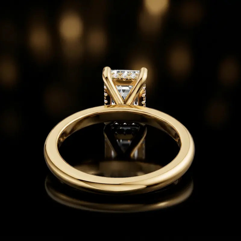 Back view of 4-claw emerald cut engagement ring with hidden halo in 18kt yellow gold