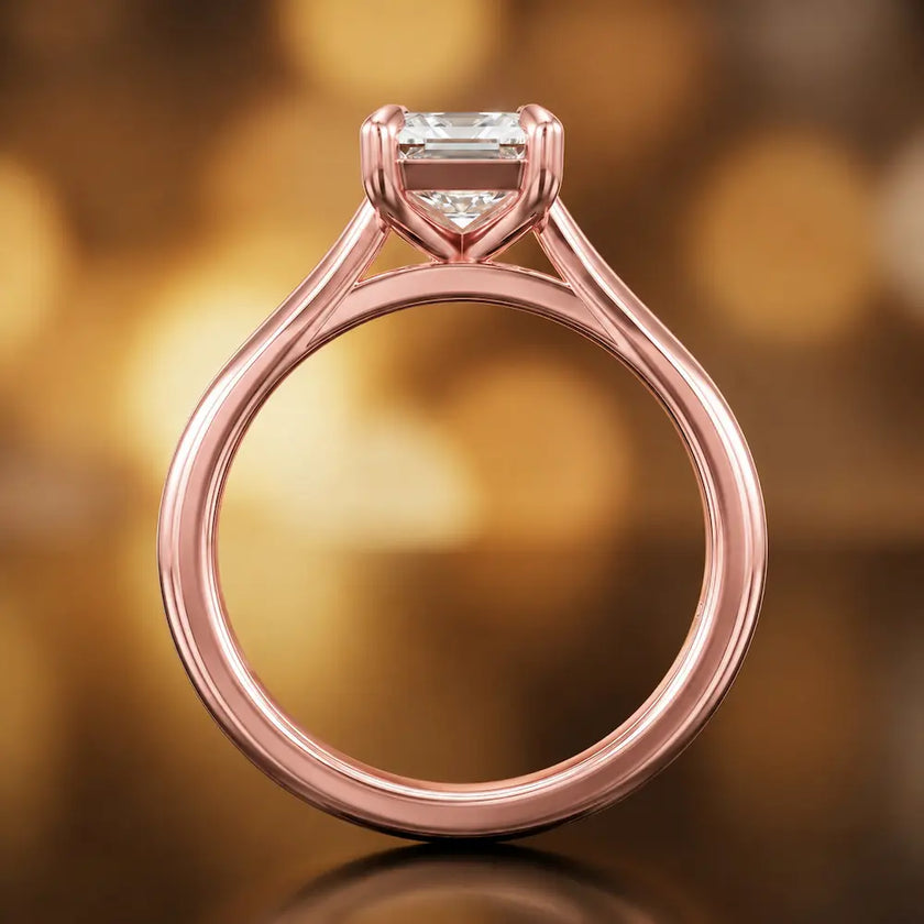 Front-on view of a 1.5 carat emerald cut diamond solitaire engagement ring showing the full 18kt rose gold band and 4 claw cathedral setting by TJ Diamond