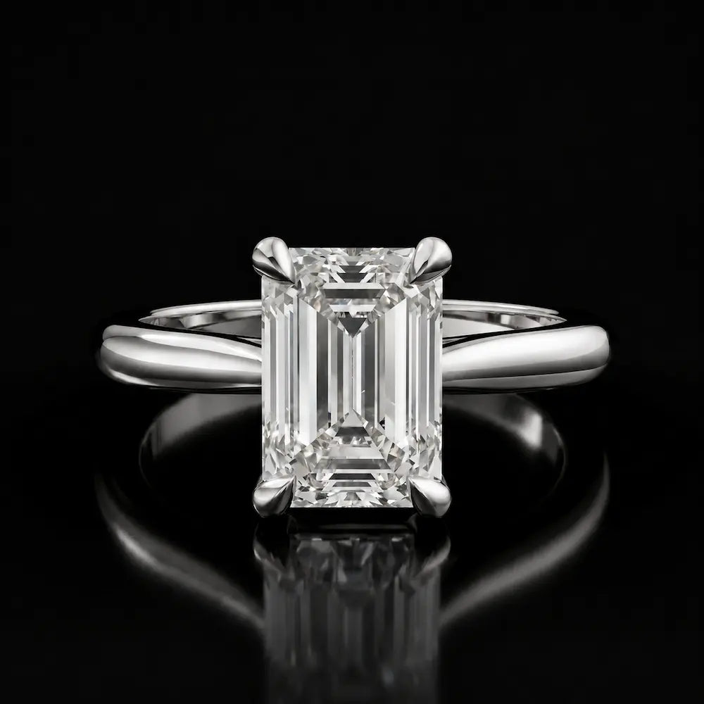 Front view of a 1.5 carat emerald cut diamond solitaire engagement ring in an 18kt white gold 4 claw setting by TJ Diamond
