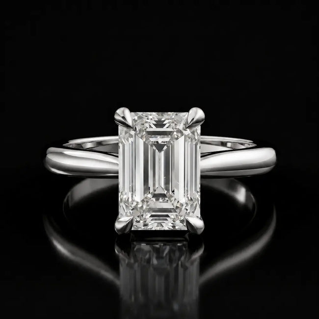Front view of a 1.5 carat emerald cut diamond solitaire engagement ring in an 18kt white gold 4 claw setting by TJ Diamond