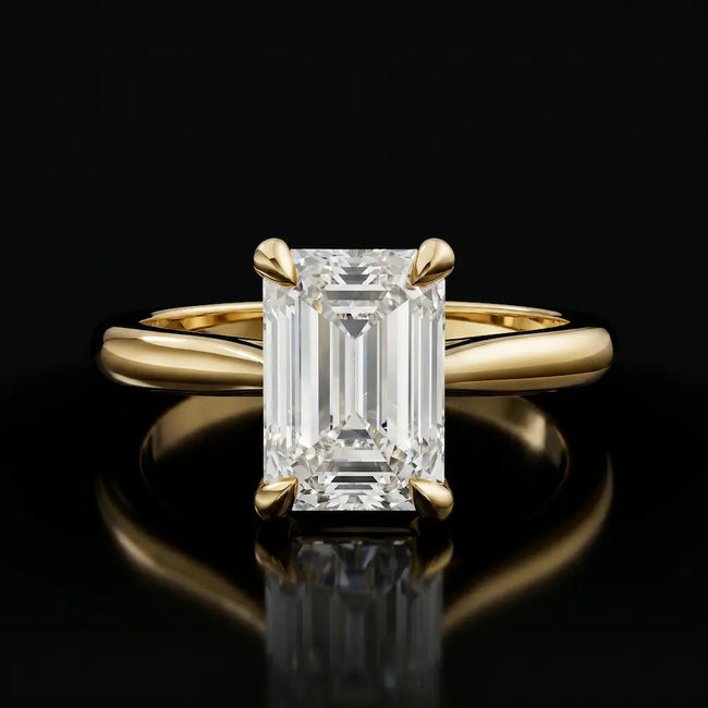 Front view of a 1.5 carat emerald cut diamond solitaire engagement ring in an 18kt yellow gold 4 claw setting by TJ Diamond