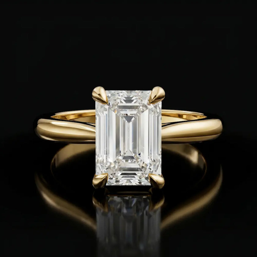 Front view of a 1.5 carat emerald cut diamond solitaire engagement ring in an 18kt yellow gold 4 claw setting by TJ Diamond