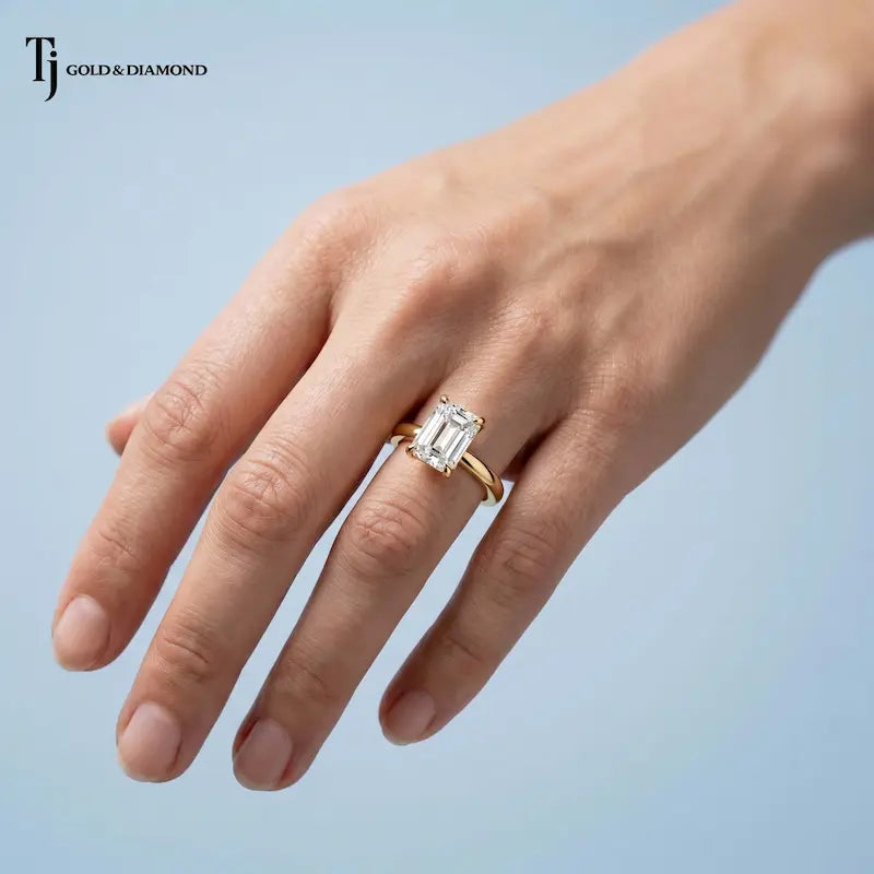 1.5 carat emerald cut lab-grown diamond solitaire engagement ring in 18kt yellow gold worn on hand