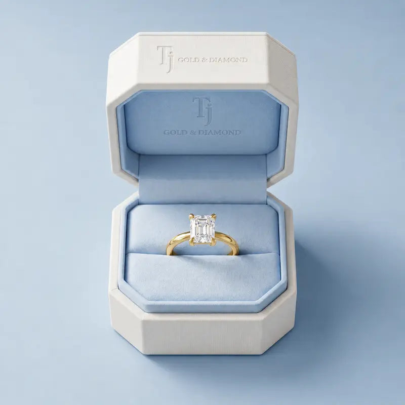 Boxed view of a 1.5 carat emerald cut lab-grown diamond solitaire engagement ring in 18kt yellow gold in a TJ Gold & Diamond box