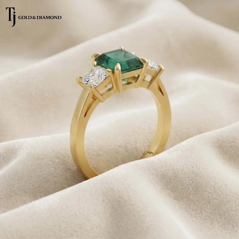Angled view of an Emerald Cut Lab-Created Emerald & Lab-Grown Diamond Trilogy Ring in 18kt yellow gold.
