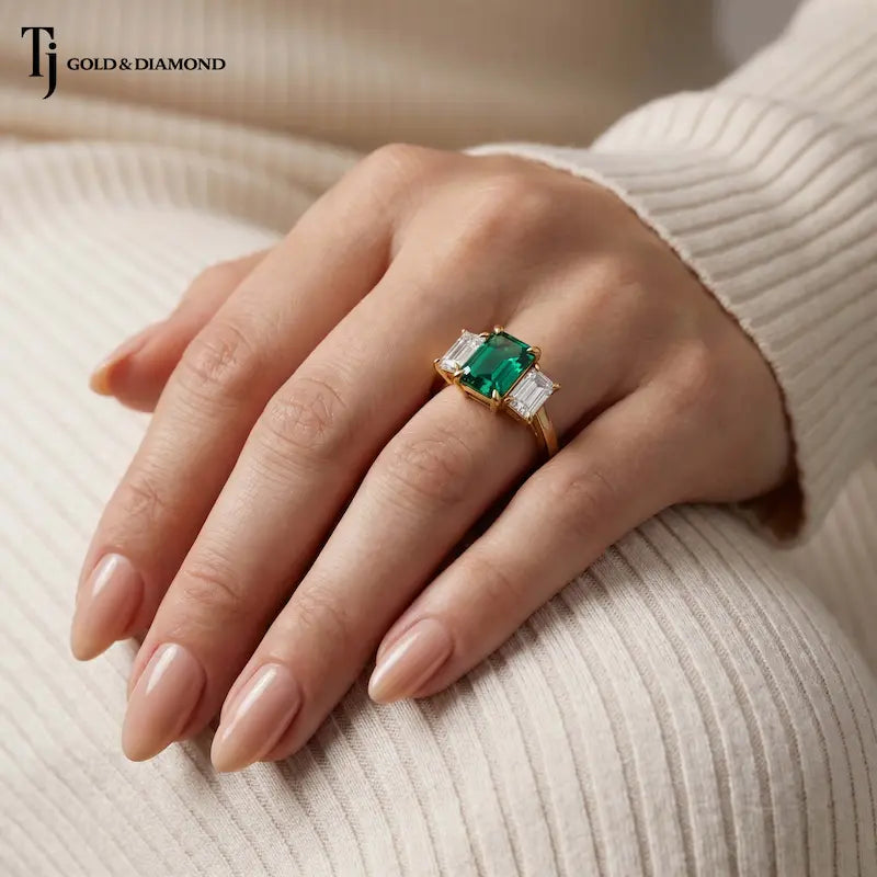 Emerald Cut Lab-Created Emerald & Lab-Grown Diamond Trilogy Ring worn on the hand in 18kt yellow gold.