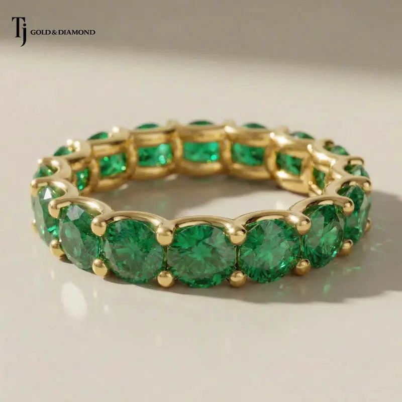 Created emerald full eternity ring in 18kt yellow gold featuring 1.5mm round brilliant lab-created emeralds in a shared prong setting.