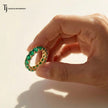 Created emerald full eternity ring in 18kt yellow gold with 1.5mm round brilliant lab-created emeralds held in hand.
