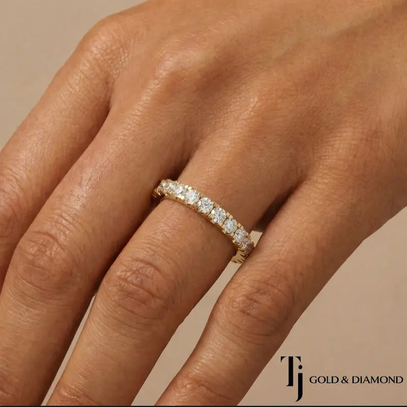 Model wearing a fish tail setting full eternity diamond wedding band in 18kt yellow gold with round brilliant lab-grown diamonds.