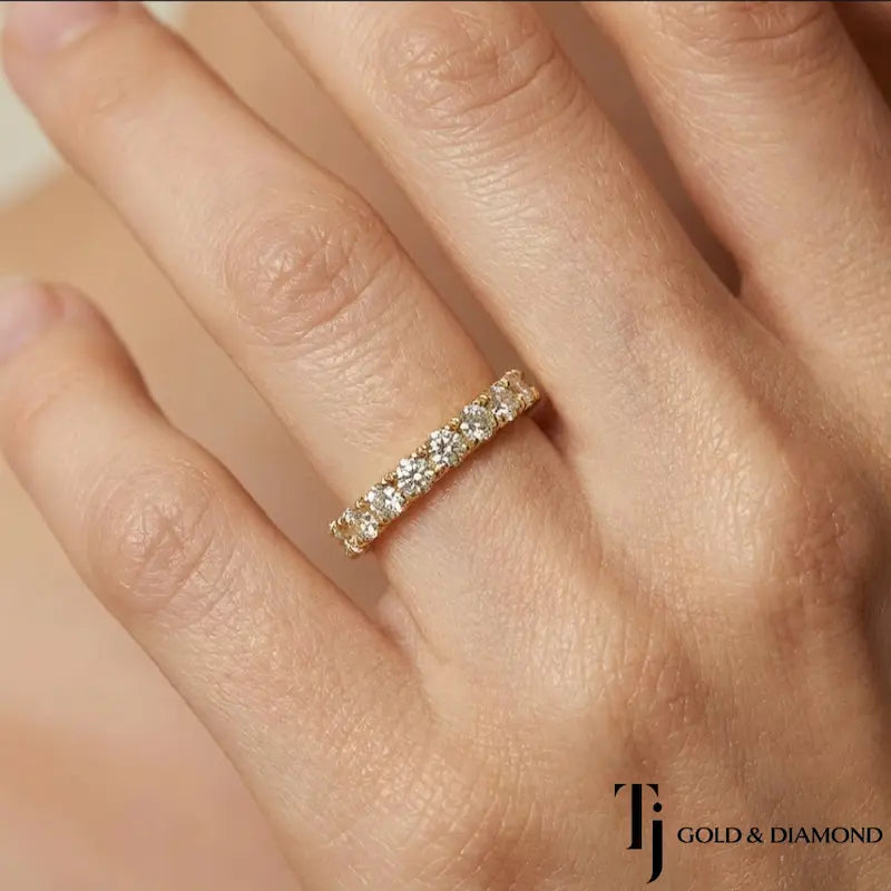 Fish tail setting full eternity diamond wedding band in 18kt yellow gold worn on finger with round brilliant lab-grown diamonds.