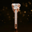 Side profile of a heart cut three-stone lab-grown diamond engagement ring in 18kt rose gold showing the diamond band