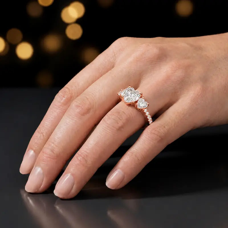 Heart cut three-stone lab-grown diamond engagement ring in 18kt rose gold with diamond shoulders worn on hand