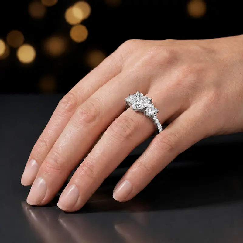 Heart cut three-stone lab-grown diamond engagement ring in 18kt white gold with diamond shoulders worn on hand