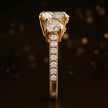  Side profile of a heart cut three-stone lab-grown diamond engagement ring in 18kt yellow gold showing the diamond band
