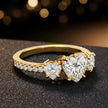 Side view of a heart cut three-stone lab-grown diamond engagement ring in 18kt yellow gold with diamond shoulders