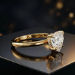 Angled view of 4-claw heart cut engagement ring with hidden halo in 18kt yellow gold