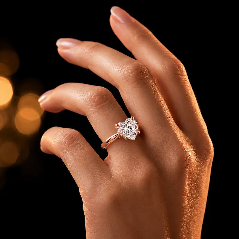 1.5 carat heart cut diamond solitaire engagement ring in an 18kt rose gold 4 claw setting worn on a hand, by TJ Diamond