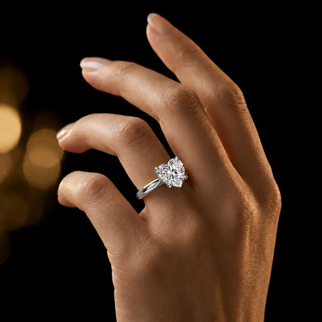 1.5 carat heart cut diamond solitaire engagement ring in an 18kt white gold 4 claw setting worn on a hand, by TJ Diamond