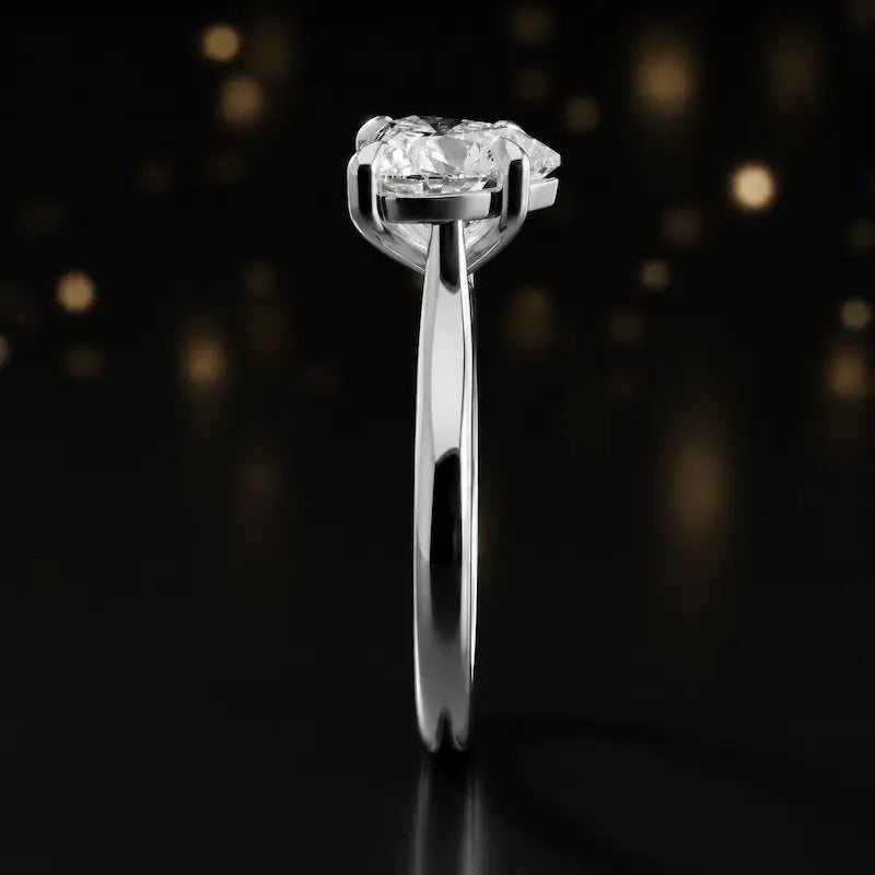 Side profile of a 1.5 carat heart cut diamond solitaire engagement ring showing the cathedral setting and 18kt white gold band by TJ Diamond