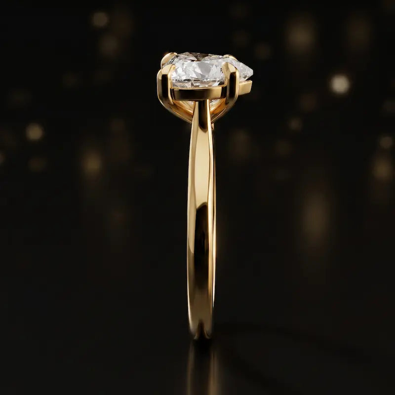 Side profile of a 1.5 carat heart cut diamond solitaire engagement ring showing the cathedral setting and 18kt yellow gold band by TJ Diamond