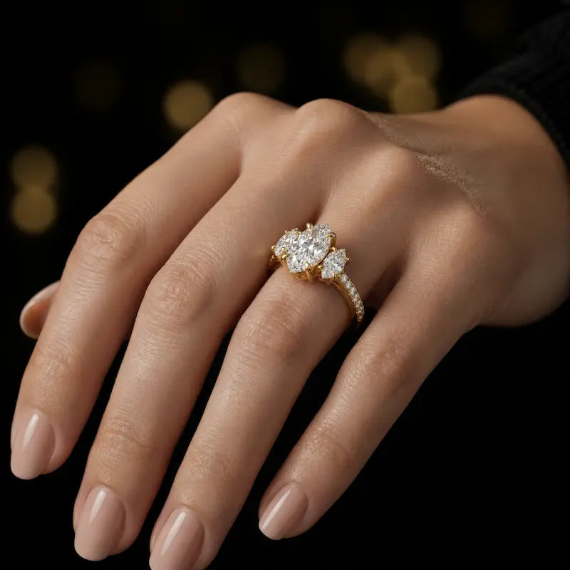 Marquise cut three-stone lab-grown diamond engagement ring in 18kt yellow gold with diamond shoulders worn on hand