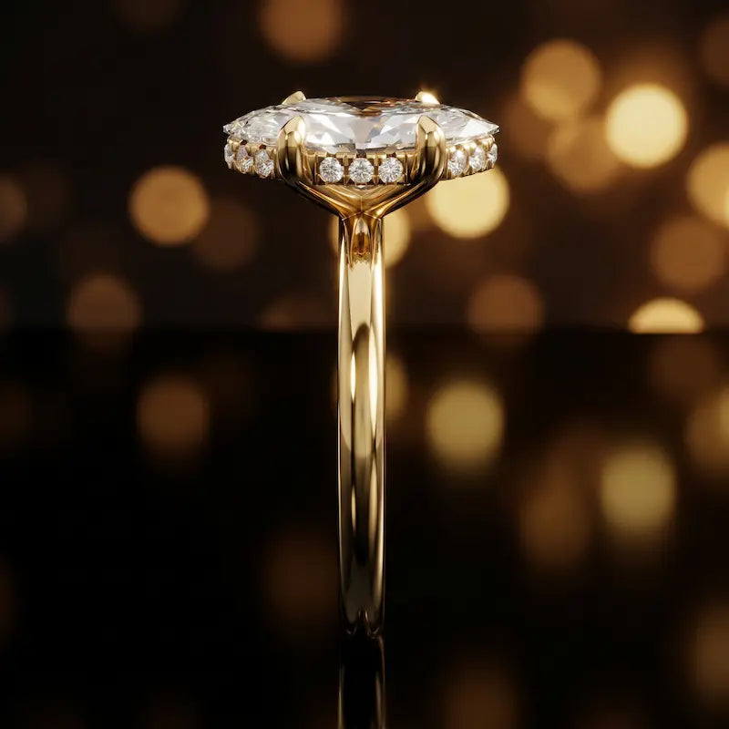 Side profile of 4-claw marquise cut engagement ring with hidden halo in 18kt yellow gold