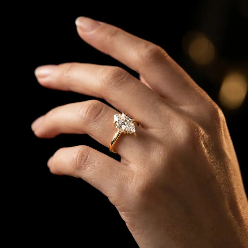 4-claw marquise cut engagement ring with hidden halo in 18kt yellow gold, worn on hand