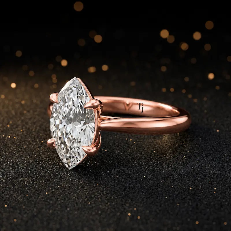 Angled side view of a 1.5 carat marquise cut diamond solitaire engagement ring in an 18kt rose gold 4 claw setting by TJ Diamond