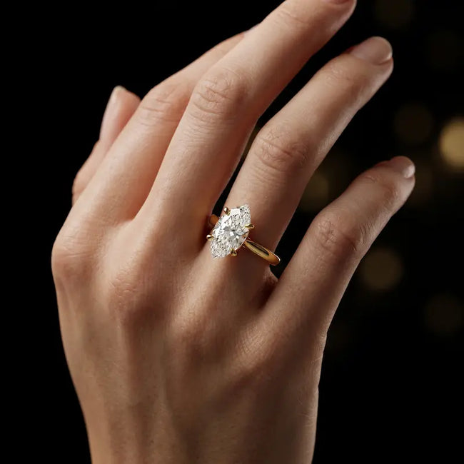 1.5 carat marquise cut diamond solitaire engagement ring in an 18kt yellow gold 4 claw setting worn on a hand, by TJ Diamond