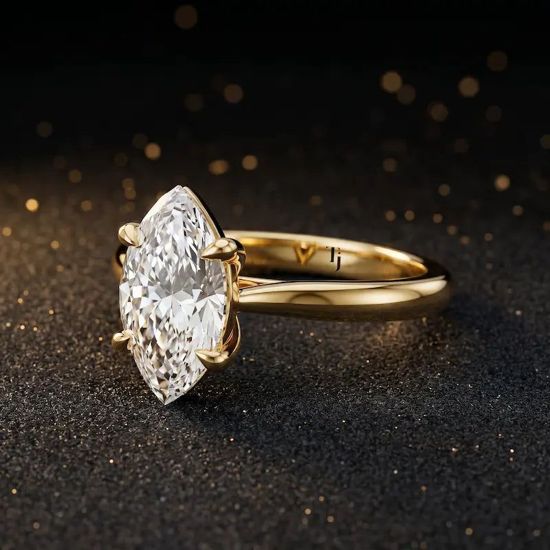 Angled side view of a 1.5 carat marquise cut diamond solitaire engagement ring in an 18kt yellow gold 4 claw setting by TJ Diamond