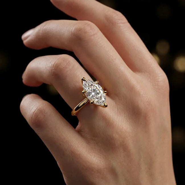 1.5 carat marquise cut diamond solitaire engagement ring in an 18kt yellow gold 6 claw setting worn on a hand, by TJ Diamond