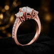 Angled view of an oval cut three-stone lab-grown diamond engagement ring in 18kt rose gold with diamond shoulders