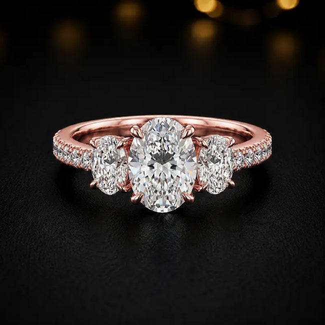 Front view of an oval cut three-stone lab-grown diamond engagement ring in 18kt rose gold with diamond shoulders