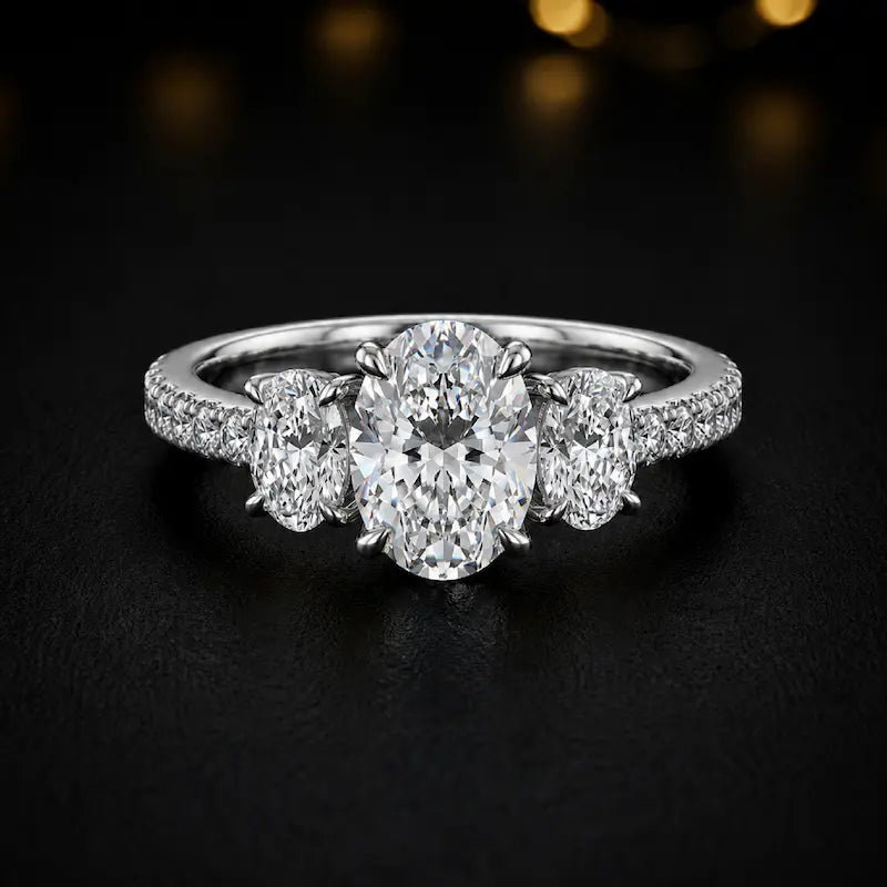 Front view of an oval cut three-stone lab-grown diamond engagement ring in 18kt white gold with diamond shoulders