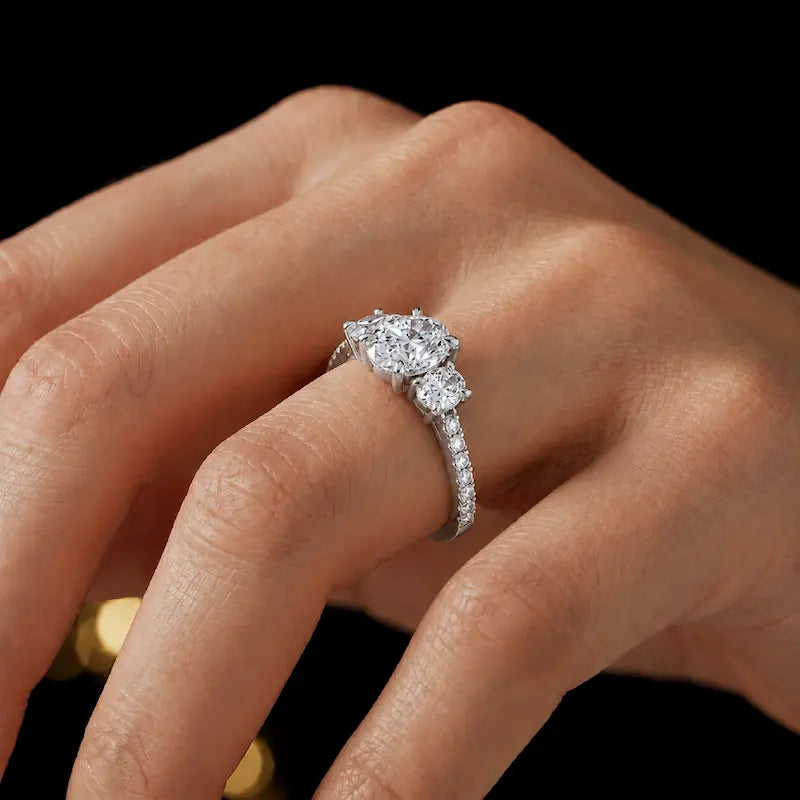 Oval cut three-stone lab-grown diamond engagement ring in 18kt white gold with diamond shoulders worn on hand
