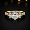Front view of an oval cut three-stone lab-grown diamond engagement ring in 18kt yellow gold with diamond shoulders