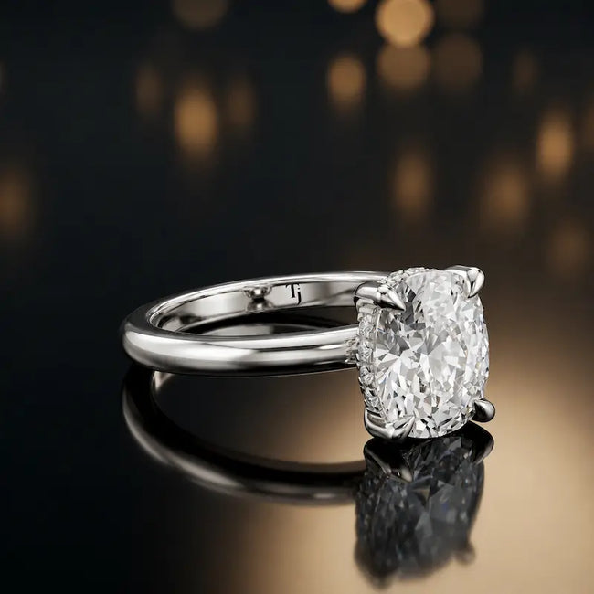 Angled view of 4-claw oval cut engagement ring with hidden halo in 18kt white gold