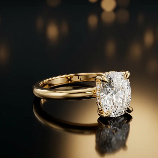 Angled view of 4-claw oval cut engagement ring with hidden halo in 18kt yellow gold