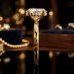 Side profile of 4-claw oval cut engagement ring with hidden halo in 18kt yellow gold