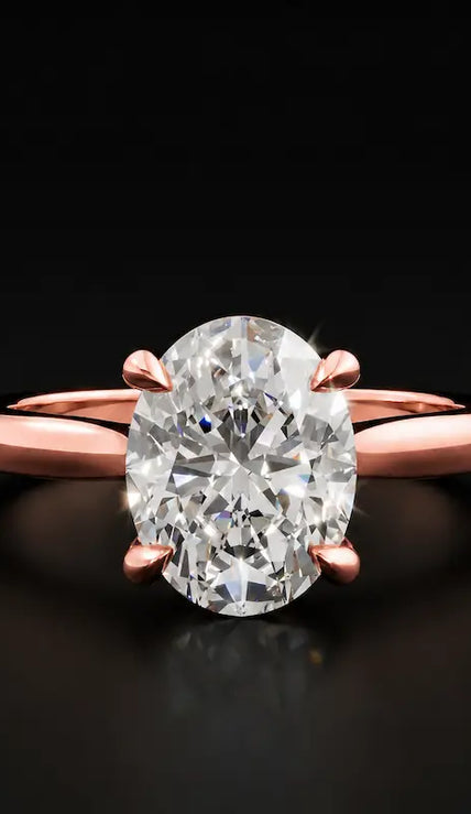 Front view of a 1.5 carat oval cut diamond solitaire engagement ring in an 18kt rose gold 4 claw setting by TJ Diamond