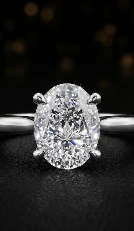 Front view of a 1.5 carat oval cut diamond solitaire engagement ring in an 18kt white gold 4 claw setting by TJ Diamond