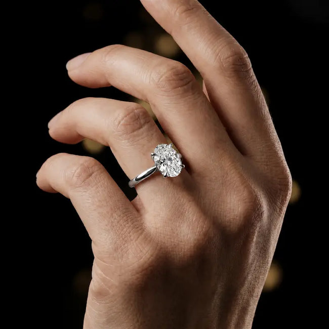 1.5 carat oval cut diamond solitaire engagement ring in an 18kt white gold 4 claw setting worn on a hand, by TJ Diamond
