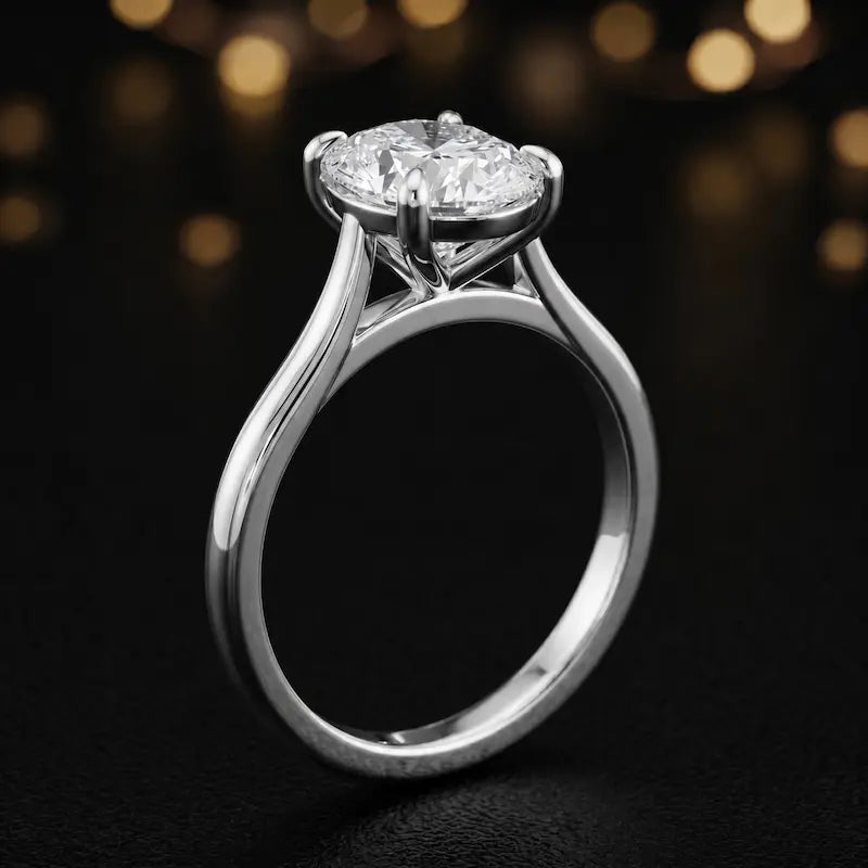 Angled side view of a 1.5 carat oval cut diamond solitaire engagement ring in an 18kt white gold 4 claw setting by TJ Diamond