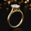 Angled side view of a 1.5 carat oval cut diamond solitaire engagement ring in an 18kt yellow gold 4 claw setting by TJ Diamond