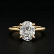 Front view of a 1.5 carat oval cut diamond solitaire engagement ring in an 18kt yellow gold 4 claw setting by TJ Diamond.