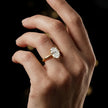 1.5 carat oval cut diamond solitaire engagement ring in an 18kt yellow gold 4 claw setting worn on a hand, by TJ Diamond