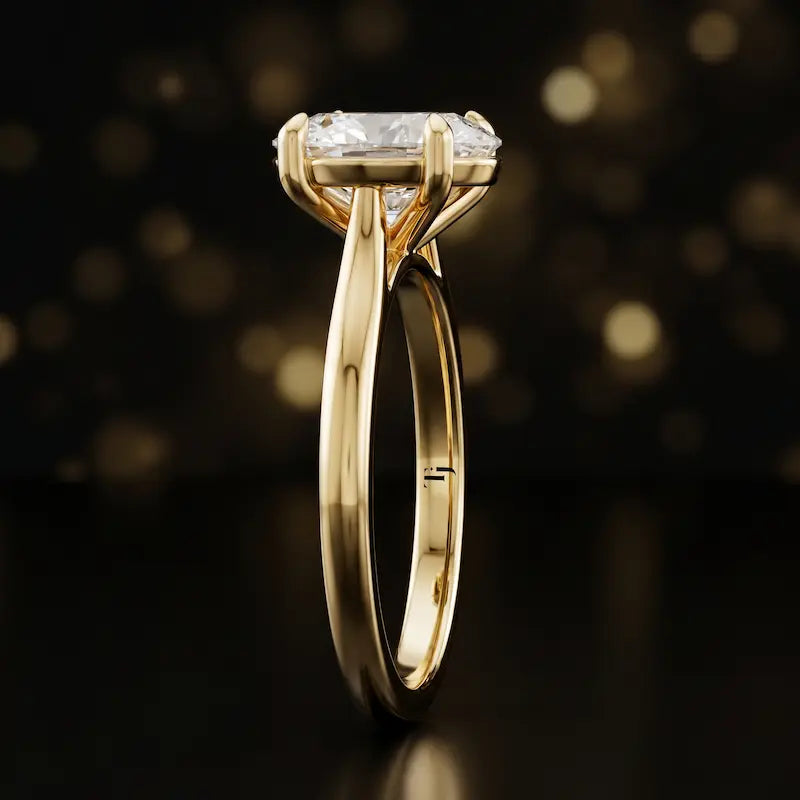 Side profile of a 1.5 carat oval cut diamond solitaire engagement ring showing the cathedral setting and 18kt yellow gold band by TJ Diamond